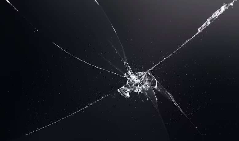 Close-up of a star-shaped impact chip with cracks radiating outward across dark glass