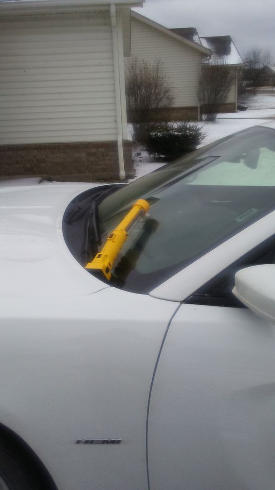 Yellow repair injector on the windshield of a white HEMI sedan in a snowy driveway