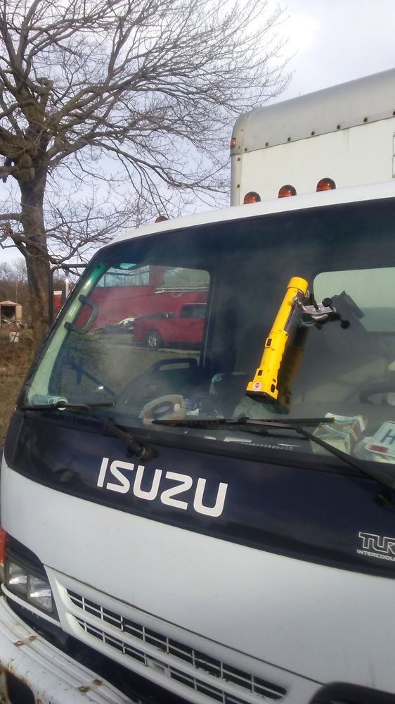 Yellow windshield repair injector on the windshield of a white Isuzu box truck