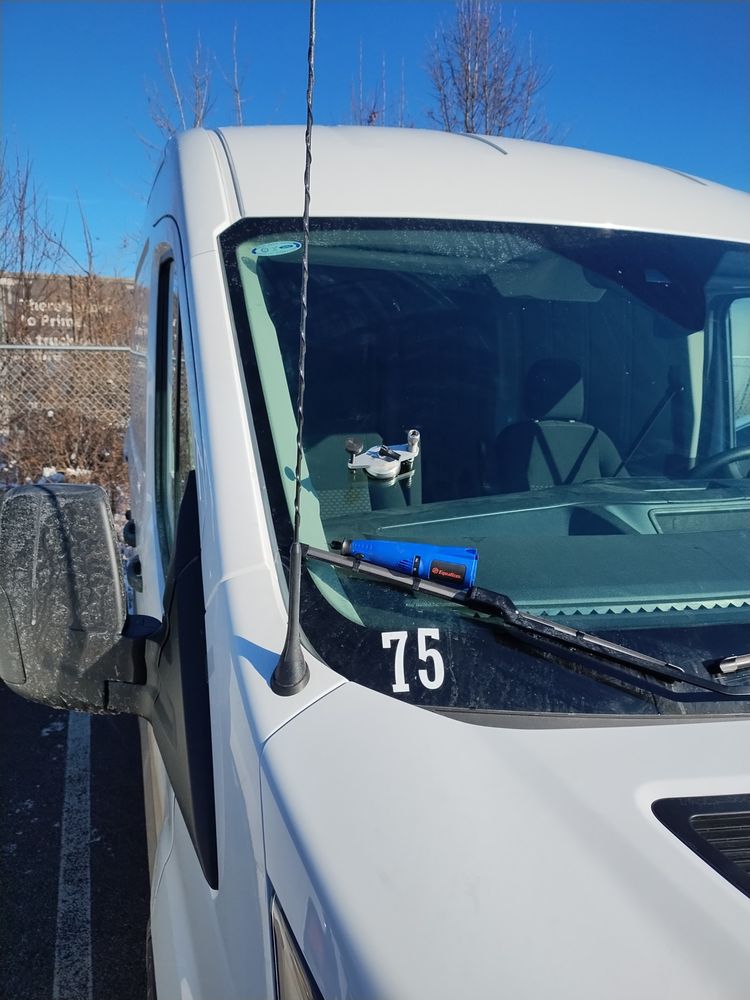 Repair tool mounted on the windshield of a white fleet van numbered 75 on a clear winter day